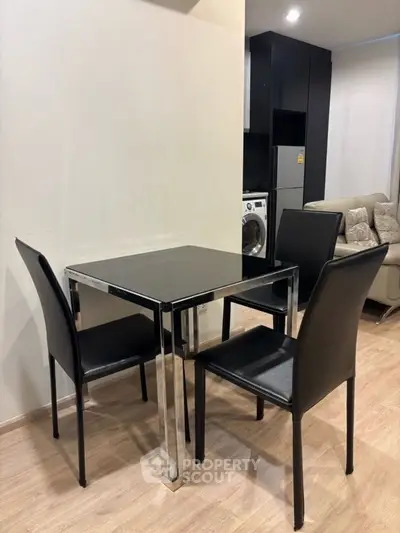 Modern apartment interior with sleek dining set and cozy living area, featuring a washing machine and stylish decor.