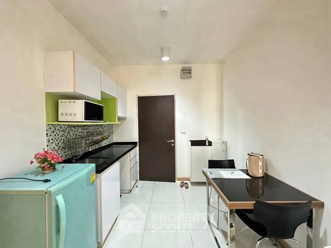 Modern kitchen with sleek design and compact dining area, featuring stylish appliances and contemporary decor.
