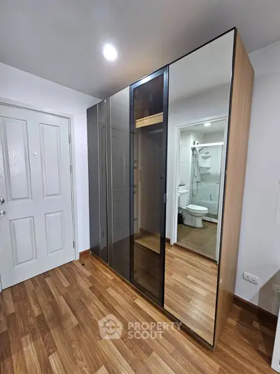 Modern bedroom with sleek mirrored wardrobe and wooden flooring