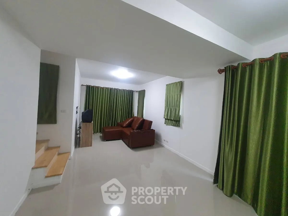 Spacious living room with modern decor and green curtains, perfect for family gatherings.