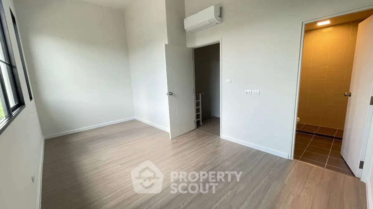 Spacious empty room with wooden flooring and attached bathroom, perfect for customization.