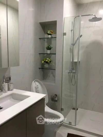 Modern bathroom with glass shower and sleek fixtures in a contemporary apartment.