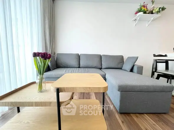 Modern living room with stylish gray sectional sofa and elegant wooden coffee table.