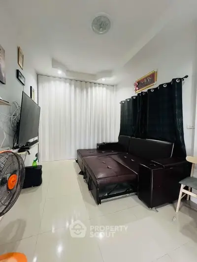 Modern living room with sleek leather sofa and large TV, perfect for relaxation and entertainment.