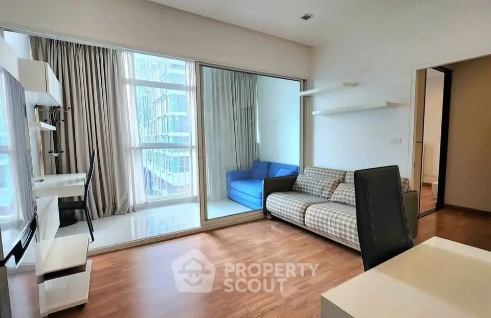 Modern living room with large windows and stylish furniture in urban apartment.