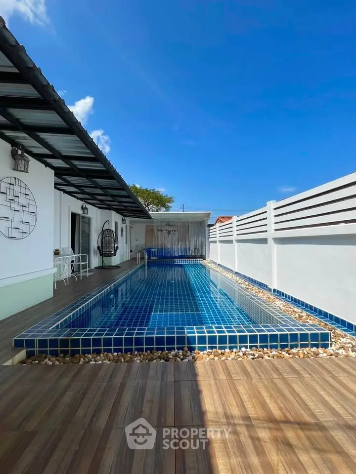 Stunning modern home with private pool and spacious deck under clear blue skies.