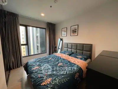 Cozy bedroom with large window and modern decor in urban apartment.