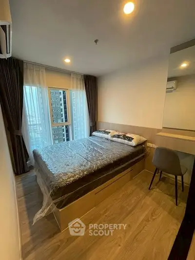Modern bedroom with city view, featuring sleek wooden flooring and stylish furnishings.