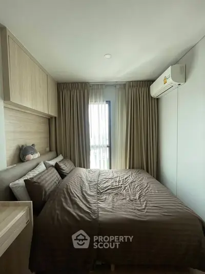 Cozy bedroom with modern decor and natural light, featuring a comfortable bed and air conditioning.