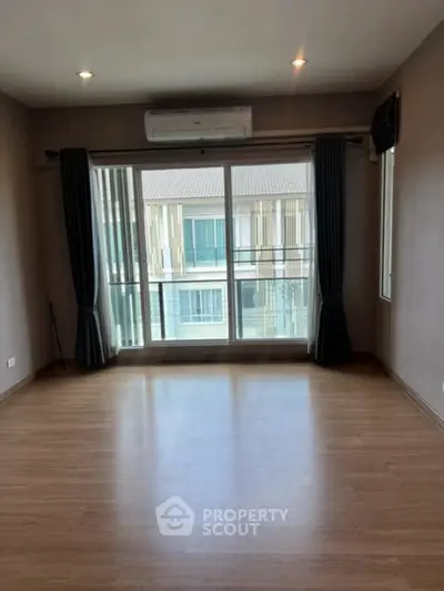 Spacious empty room with large windows and balcony access in modern apartment.