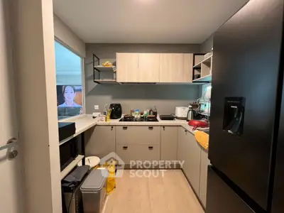 Modern kitchen with sleek cabinets and black refrigerator, featuring open layout and ample storage space.