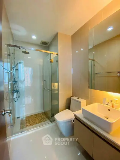 Modern bathroom with glass shower and sleek fixtures in a contemporary apartment.