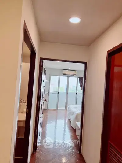Bright hallway leading to a cozy bedroom with balcony access in modern apartment.