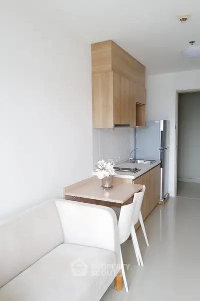 Modern minimalist kitchen with sleek cabinetry and cozy dining area in a bright apartment.