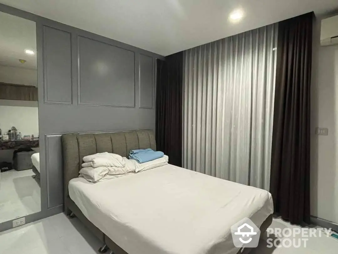 Elegant bedroom with a large bed, sleek built-in cabinets, and luxurious floor-to-ceiling curtains, offering a serene and sophisticated sleeping space.