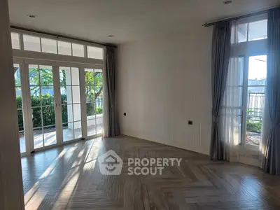 Spacious living room with large windows and garden view, perfect for natural light lovers.
