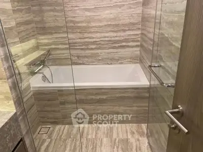 Luxurious bathroom with elegant marble tiles and a sleek bathtub, perfect for relaxation.