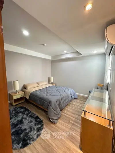 Cozy bedroom with modern decor and wooden flooring, featuring a comfortable bed and stylish lighting.