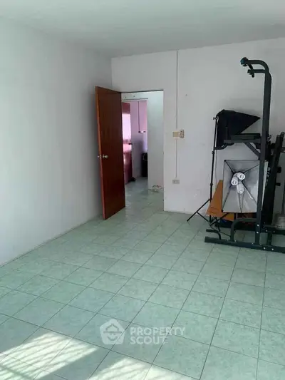 Spacious room with exercise equipment and tiled flooring, ideal for home gym setup.