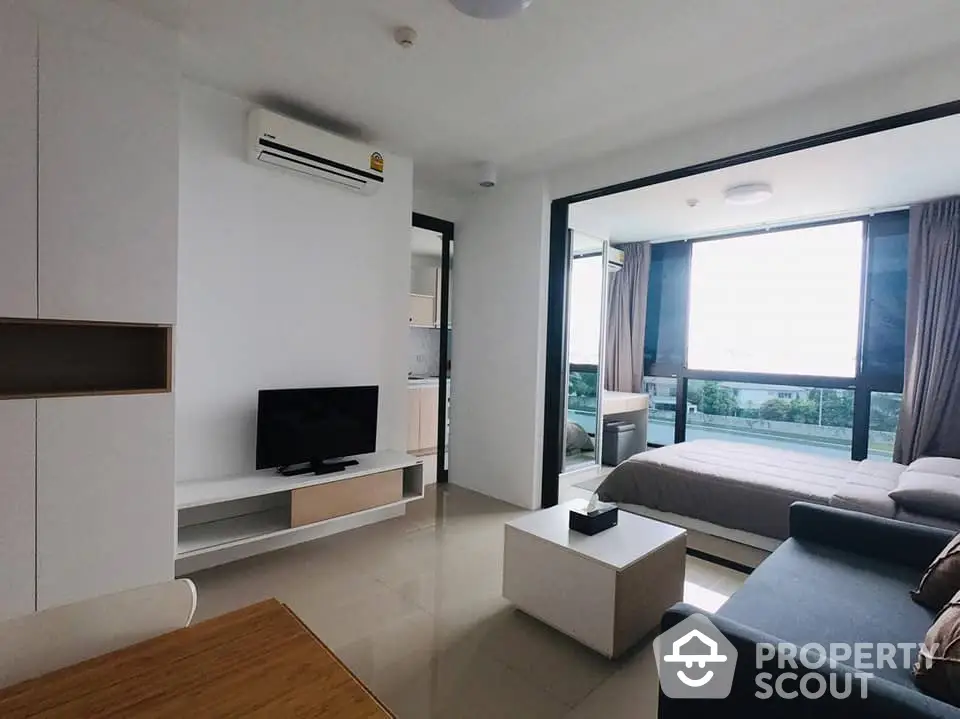 Modern studio apartment with seamless living and sleeping areas, featuring sleek furnishings, ample natural light, and a cozy balcony with a view.