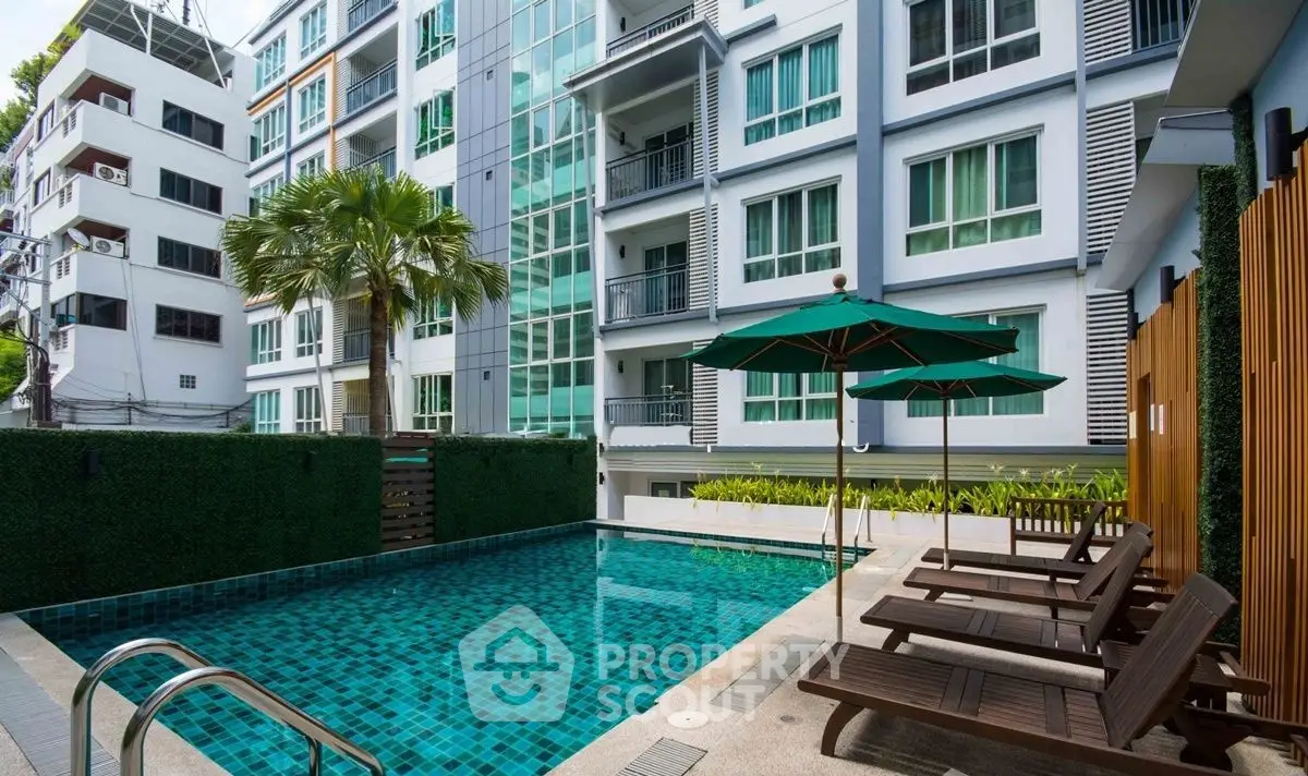 Modern apartment building with poolside relaxation area and lush greenery.