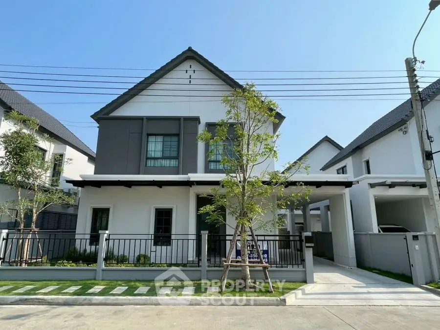 Modern two-story house with sleek design and spacious driveway in suburban neighborhood.