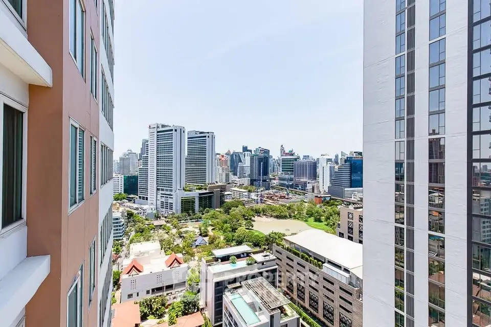 Stunning cityscape view from high-rise building balcony, showcasing urban skyline and lush greenery.