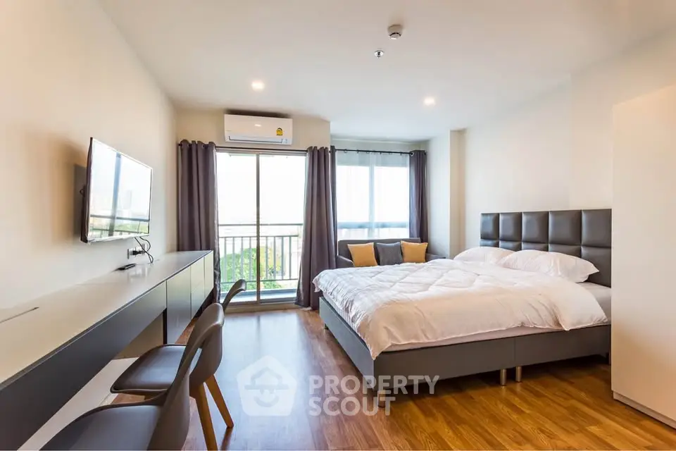 Modern bedroom with balcony view, stylish furniture, and natural light in a contemporary apartment.
