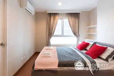 Cozy bedroom with a large comfortable bed, stylish red accents, and modern air conditioning, perfect for relaxation and a good night's sleep.