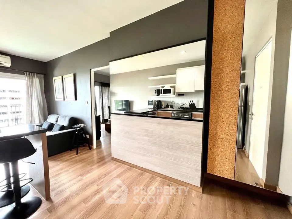 Modern open-plan living room with sleek kitchen and cozy seating area in stylish apartment.