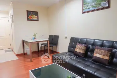 Cozy living room with modern black sofa and dining area, perfect for relaxation and entertaining.