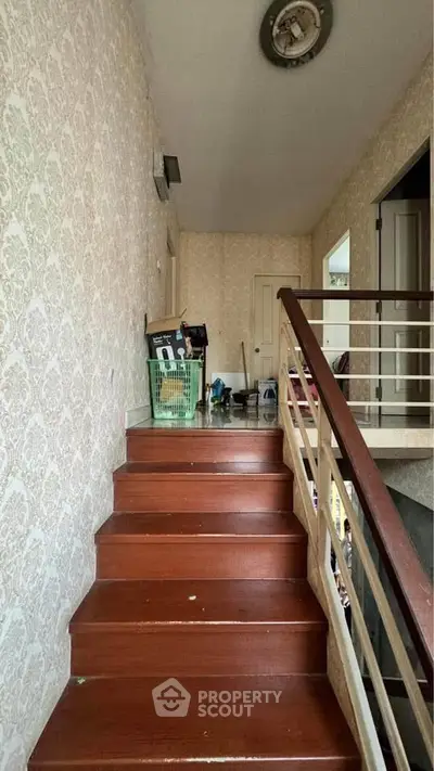 Charming staircase with wooden steps and elegant wallpaper in a cozy home setting.