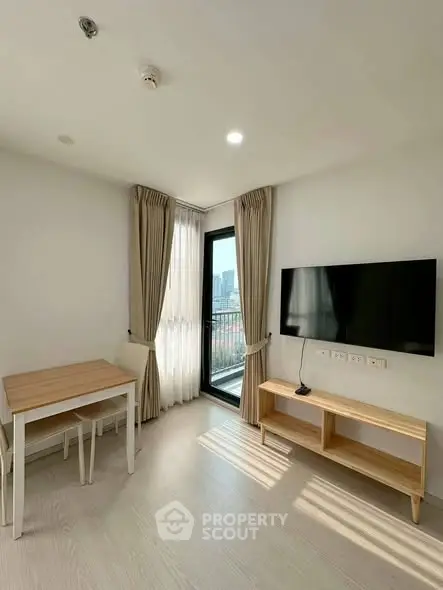 Modern living room with natural light, sleek TV setup, and cozy dining area.