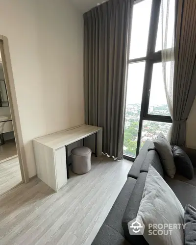 Spacious high-rise living room with floor-to-ceiling windows offering panoramic city views, complemented by modern furniture and elegant drapery.