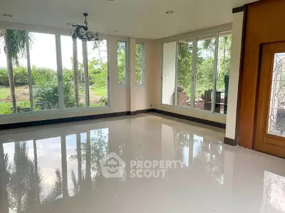 Spacious living room with large windows and garden view, perfect for natural light lovers.