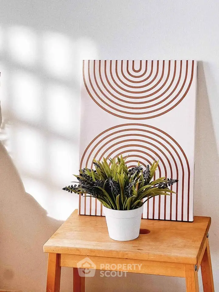 Stylish interior decor with modern art and plant on wooden stool