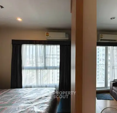 Modern bedroom with large windows and city view, featuring air conditioning and contemporary design.