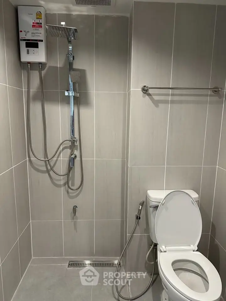 Modern bathroom with sleek shower and toilet in minimalist design.