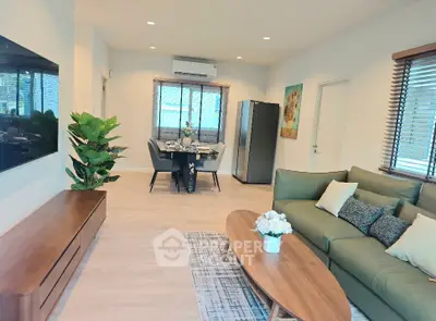 Modern living room with stylish furniture and open dining area, featuring a large TV and elegant decor.