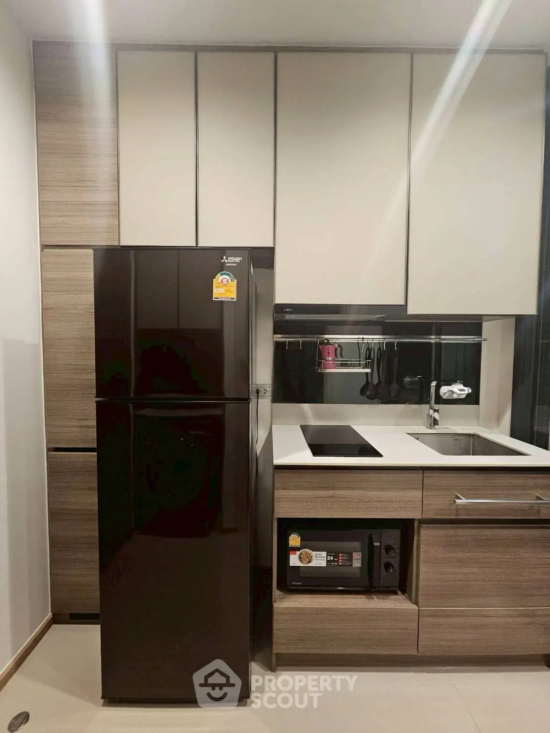 Modern kitchen with sleek cabinetry and appliances, featuring a black fridge and built-in oven.