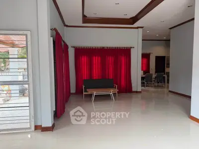 Spacious living room with red curtains and modern furniture, perfect for family gatherings.