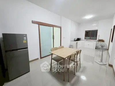 Modern kitchen with sleek dining table and stainless steel fridge in bright open space.