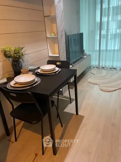 Modern living room with dining area, sleek furniture, and large window for natural light.