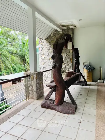 Spacious balcony with unique wooden sculptures and lush greenery view