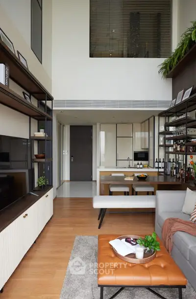 Modern living room with high ceiling, stylish shelving, and cozy seating area in a contemporary apartment.