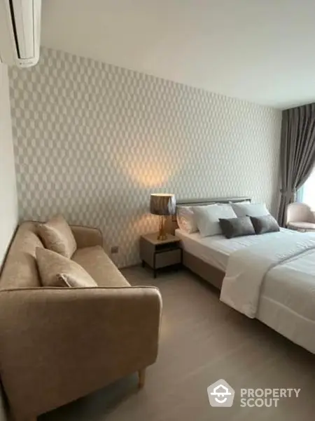 Elegant bedroom with stylish patterned wallpaper, cozy beige sofa, and a comfortable king-sized bed illuminated by a chic bedside lamp.