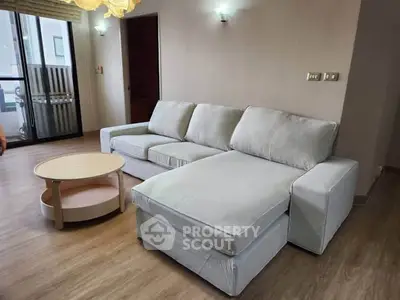 Spacious living room with modern sectional sofa and wooden flooring, perfect for relaxation.