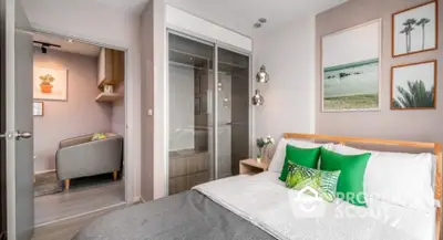 Modern bedroom with stylish decor and green accents, featuring a cozy sitting area and framed artwork.