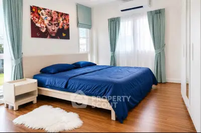 Modern bedroom with blue bedding, wooden flooring, and stylish wall art.