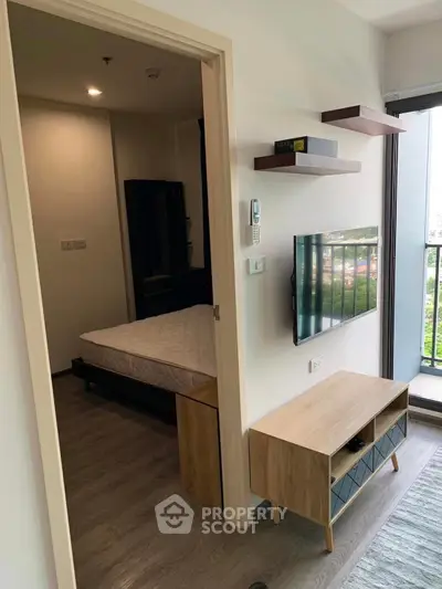 Modern apartment interior with bedroom and living area, featuring sleek furniture and balcony access.